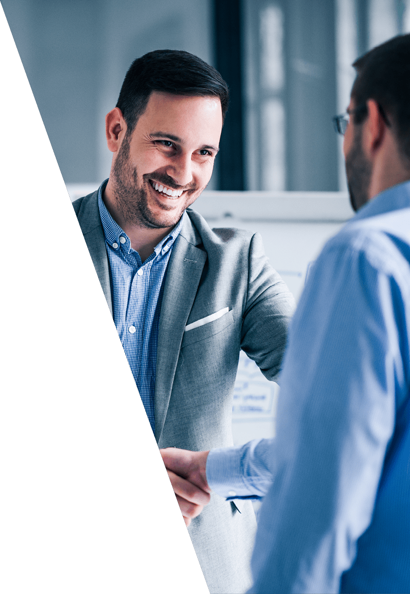 Two smiling businessmen shaking hands while standing in an office 